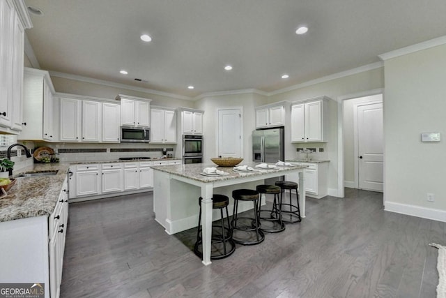 kitchen featuring stainless steel appliances, a sink, a center island, white cabinets, and recessed lighting