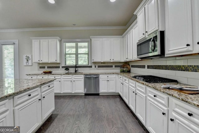 kitchen with stainless steel appliances, a sink, white cabinets, ornamental molding, and decorative backsplash