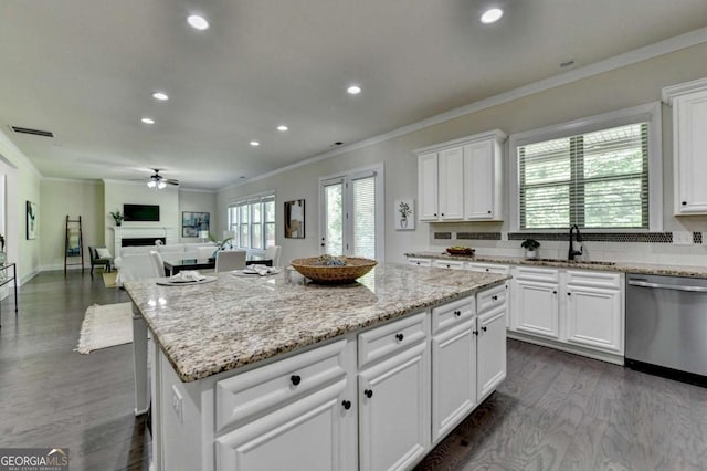 kitchen featuring stainless steel dishwasher, a sink, ceiling fan, ornamental molding, and white cabinetry