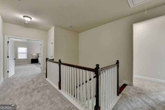 hall featuring attic access, carpet, an upstairs landing, and baseboards