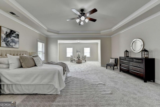 carpeted bedroom featuring a tray ceiling, crown molding, baseboards, and a ceiling fan