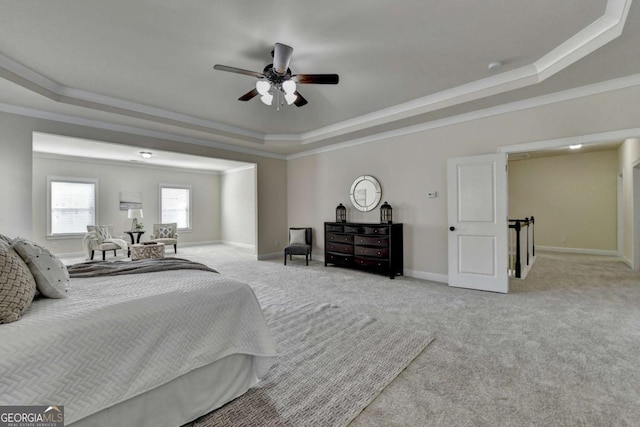 bedroom with a raised ceiling, carpet flooring, crown molding, baseboards, and ceiling fan