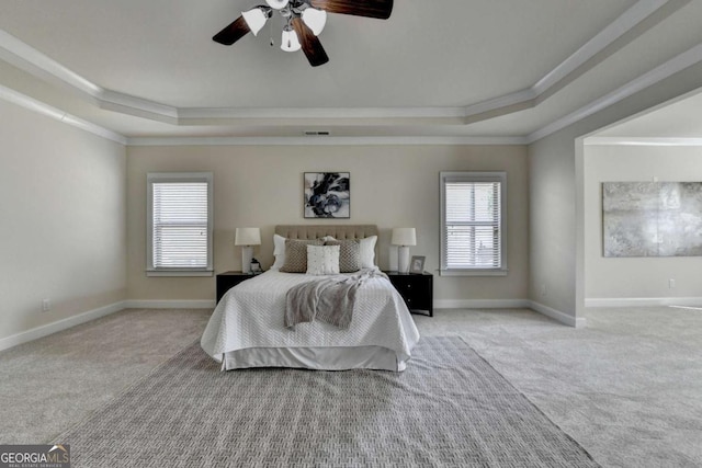 bedroom featuring a tray ceiling, ornamental molding, multiple windows, and carpet