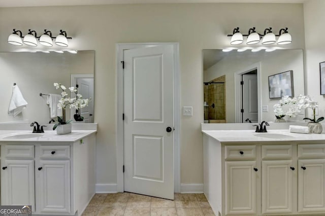 bathroom with two vanities, a tile shower, tile patterned flooring, and baseboards