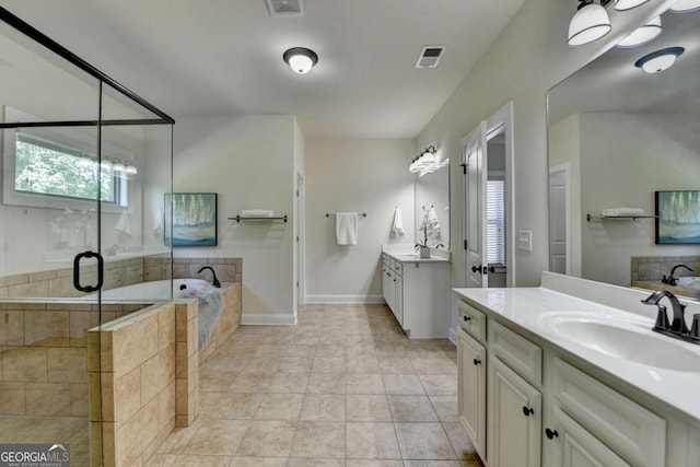 bathroom with a shower stall, a garden tub, two vanities, tile patterned flooring, and baseboards