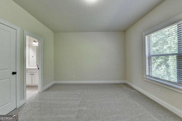 unfurnished room with plenty of natural light, light carpet, and baseboards