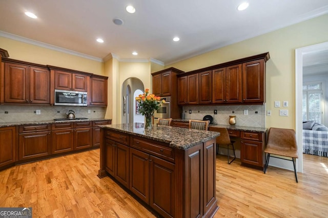 3127 Lenox Rd NE Unit 1, Atlanta, GA 30324 - kitchen with tasteful backsplash, light wood-type flooring, arched walkways, a kitchen island, and appliances with stainless steel finishes