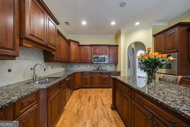 3127 Lenox Rd NE Unit 1, Atlanta, GA 30324 - kitchen featuring light wood-style flooring, a sink, arched walkways, appliances with stainless steel finishes, and ornamental molding