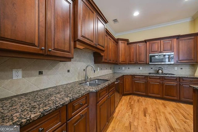3127 Lenox Rd NE Unit 1, Atlanta, GA 30324 - kitchen featuring dark stone countertops, a sink, crown molding, light wood-type flooring, and appliances with stainless steel finishes
