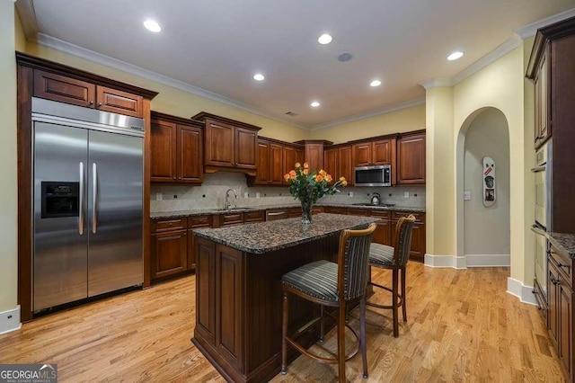 3127 Lenox Rd NE Unit 1, Atlanta, GA 30324 - kitchen featuring a sink, ornamental molding, a kitchen breakfast bar, arched walkways, and appliances with stainless steel finishes