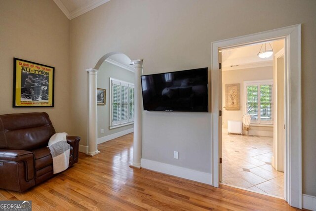 3127 Lenox Rd NE Unit 1, Atlanta, GA 30324 - living area featuring decorative columns, crown molding, arched walkways, baseboards, and light wood-style floors