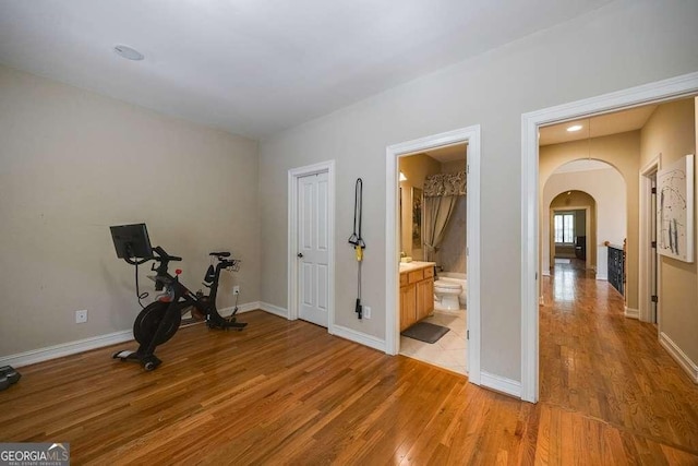 3127 Lenox Rd NE Unit 1, Atlanta, GA 30324 - exercise room featuring arched walkways, baseboards, and light wood-style flooring