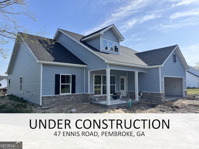 47 Ennis Rd, Pembroke, GA 31321 - view of front of property with a porch, an attached garage, a shingled roof, and brick siding