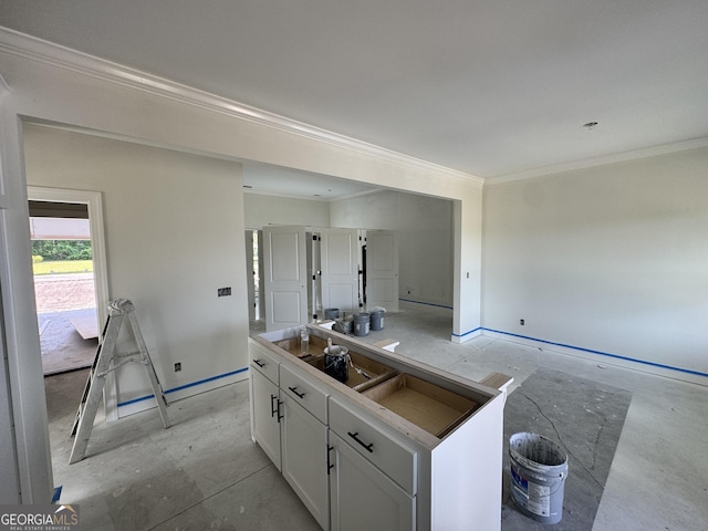 47 Ennis Rd, Pembroke, GA 31321 - kitchen featuring concrete flooring, baseboards, crown molding, white cabinetry, and a kitchen island