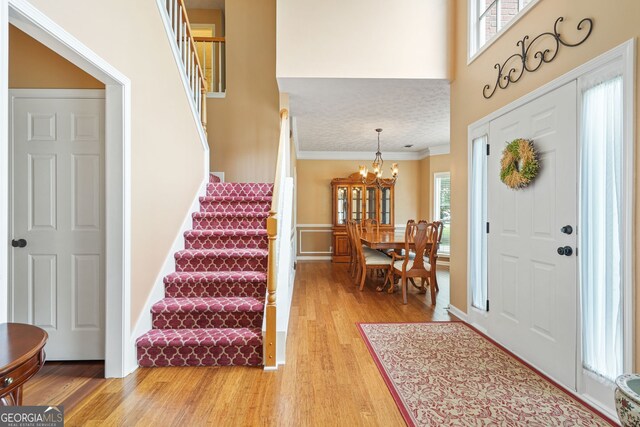 5070 Saddle Bridge Ln, Alpharetta, GA 30022 - foyer entrance with stairway, light wood finished floors, a chandelier, ornamental molding, and a high ceiling