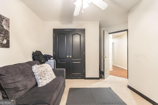 carpeted living room with baseboards and a ceiling fan