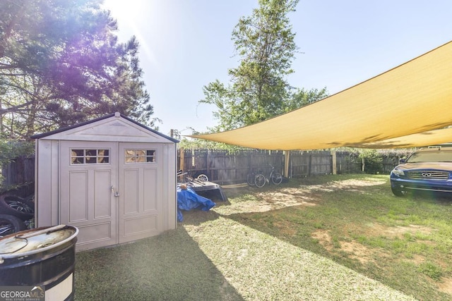 view of yard featuring a storage shed, an outdoor structure, and a fenced backyard