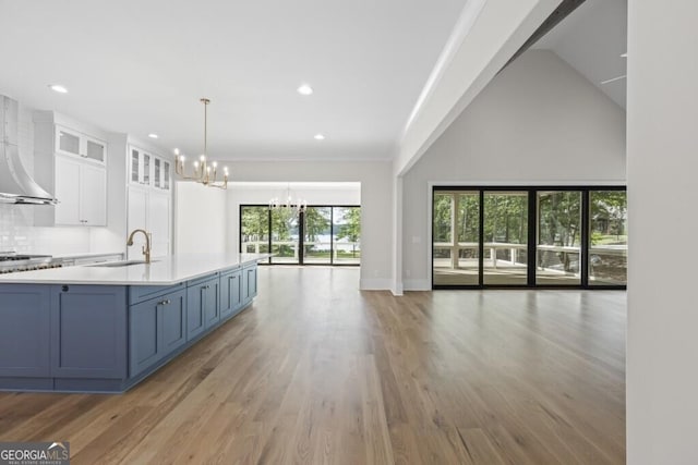 1301 Grayson Pointe Dr, Buckhead, GA 30625 - kitchen with open floor plan, a chandelier, a sink, white cabinetry, and wall chimney exhaust hood