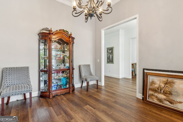 sitting room with a chandelier, dark wood finished floors, baseboards, and ornamental molding