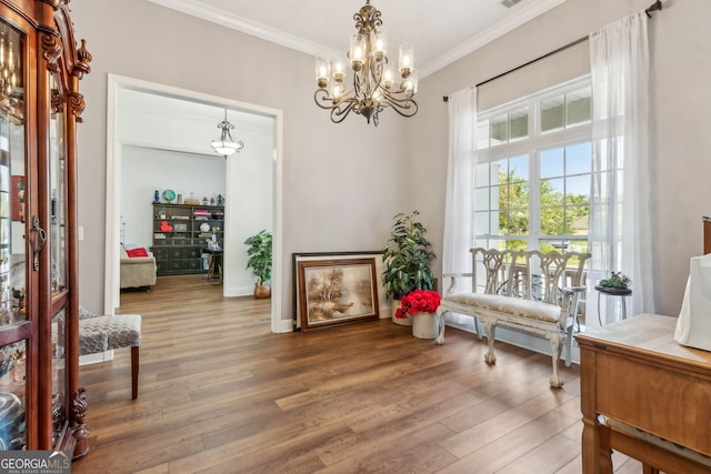 living area featuring ornamental molding, a chandelier, wood finished floors, and baseboards