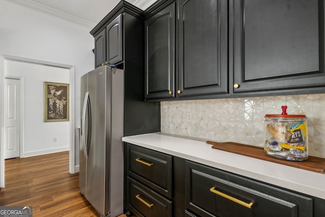 kitchen with crown molding, backsplash, dark cabinets, light countertops, and dark wood-style floors