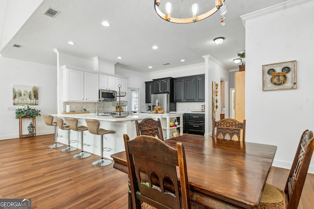 dining room featuring ornamental molding, wood finished floors, recessed lighting, and baseboards