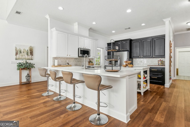 kitchen with appliances with stainless steel finishes, crown molding, a breakfast bar area, backsplash, and light countertops