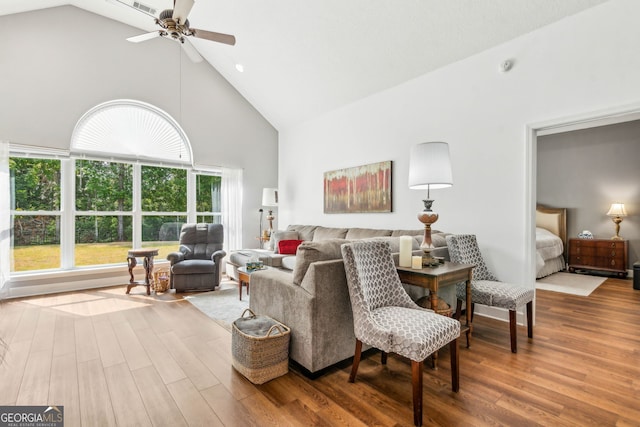 living area with high vaulted ceiling, a ceiling fan, and wood finished floors