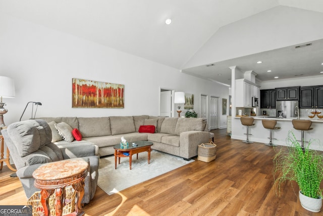 living area with wood finished floors, high vaulted ceiling, and recessed lighting