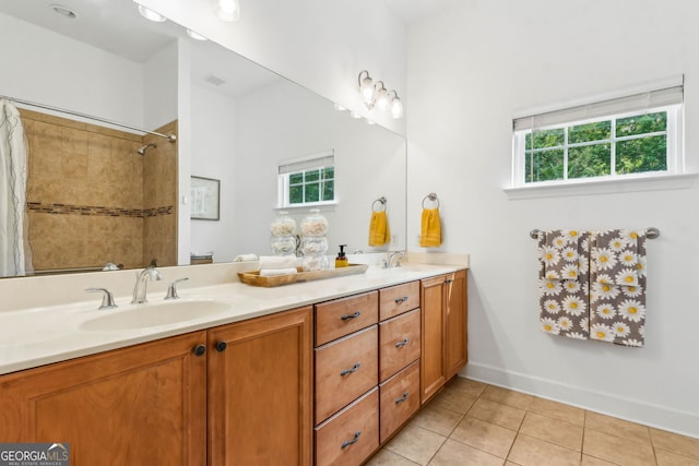 bathroom featuring plenty of natural light, tile patterned flooring, a tile shower, and double vanity