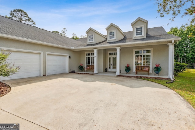 cape cod house with stucco siding, french doors, driveway, and an attached garage
