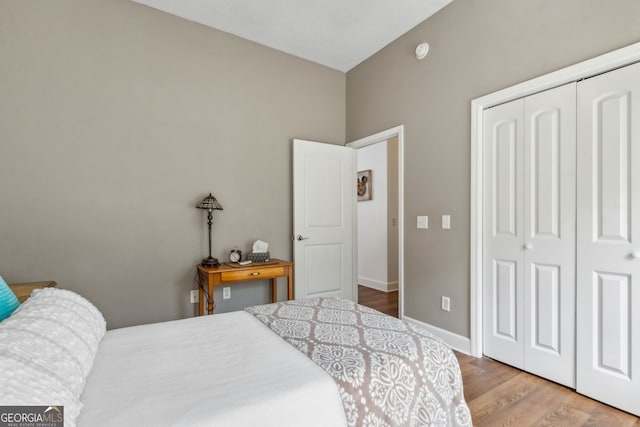 bedroom with a closet, wood finished floors, and baseboards