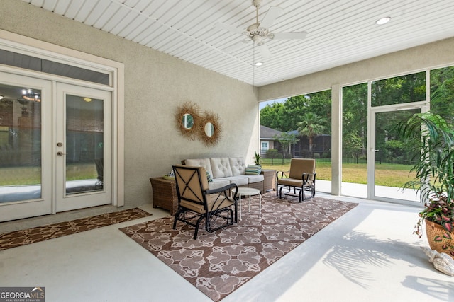 sunroom / solarium with french doors, finished concrete flooring, a ceiling fan, an outdoor living space, and a textured wall