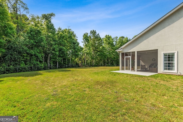 view of green lawn featuring a sunroom and a patio area