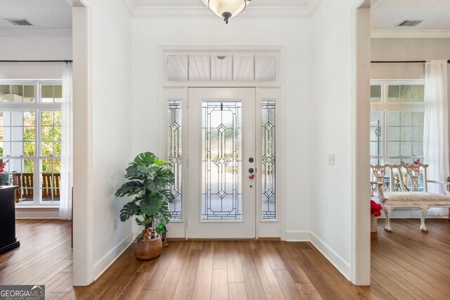 foyer featuring wood finished floors, baseboards, and ornamental molding