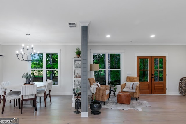interior space featuring wood finished floors, baseboards, visible vents, crown molding, and a notable chandelier