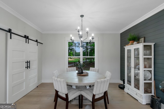 dining room featuring ornamental molding, light wood-style flooring, a barn door, and a notable chandelier