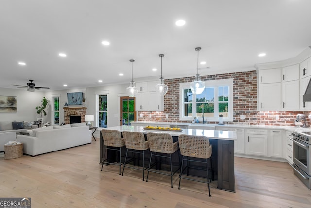 kitchen featuring a sink, open floor plan, white cabinets, electric stove, and light countertops