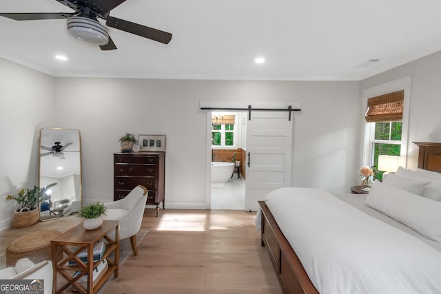 bedroom with light wood-style floors, recessed lighting, a barn door, and multiple windows