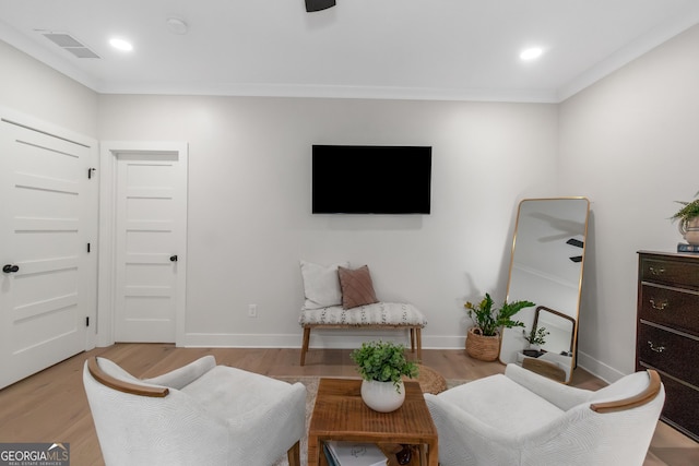 living area with light wood finished floors, ornamental molding, baseboards, and visible vents