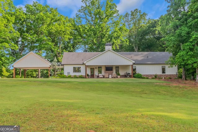 rear view of property with roof with shingles, a chimney, and a lawn