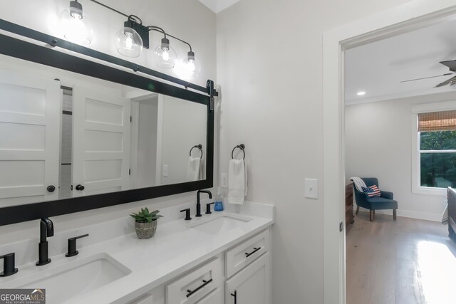 full bathroom with a sink, double vanity, baseboards, and wood finished floors