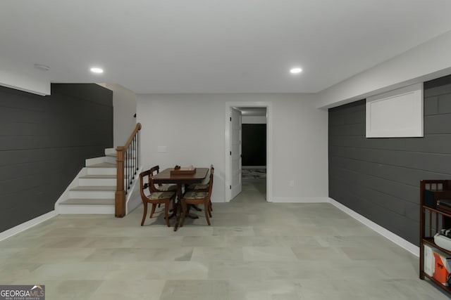 basement featuring stairway, wood walls, baseboards, and recessed lighting
