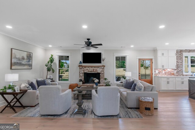 living area featuring a ceiling fan, recessed lighting, crown molding, light wood-style floors, and a fireplace