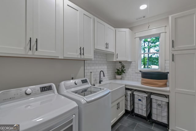 washroom with a sink, cabinet space, dark tile patterned floors, visible vents, and washer and dryer