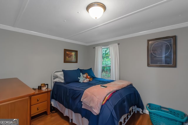 bedroom with crown molding and wood finished floors