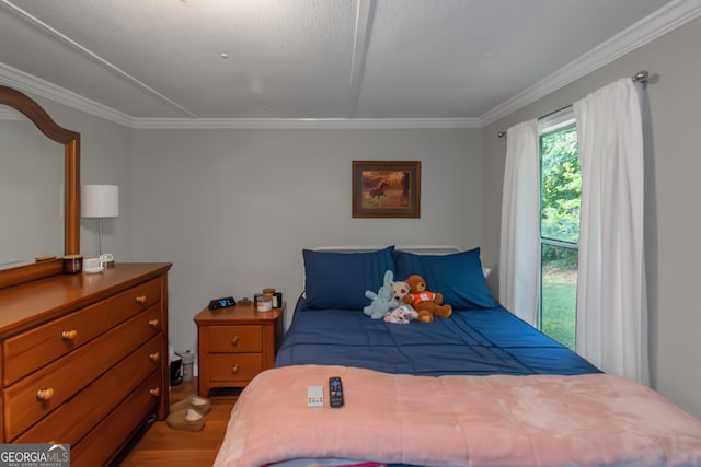 bedroom with crown molding and wood finished floors