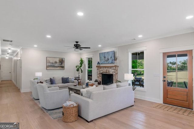 living area with baseboards, a ceiling fan, a fireplace, and light wood-style flooring