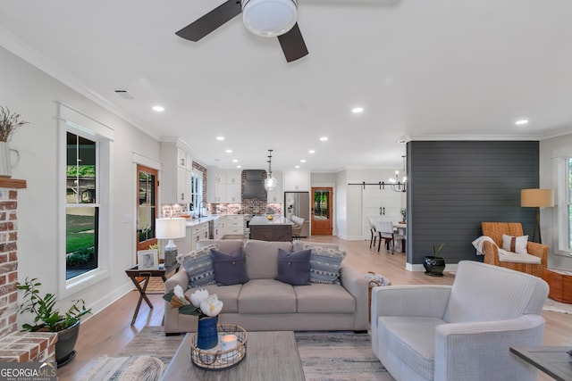 living area with ceiling fan with notable chandelier, visible vents, recessed lighting, light wood finished floors, and crown molding