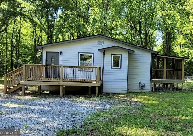 rear view of house with stairs, a deck, a sunroom, and a lawn